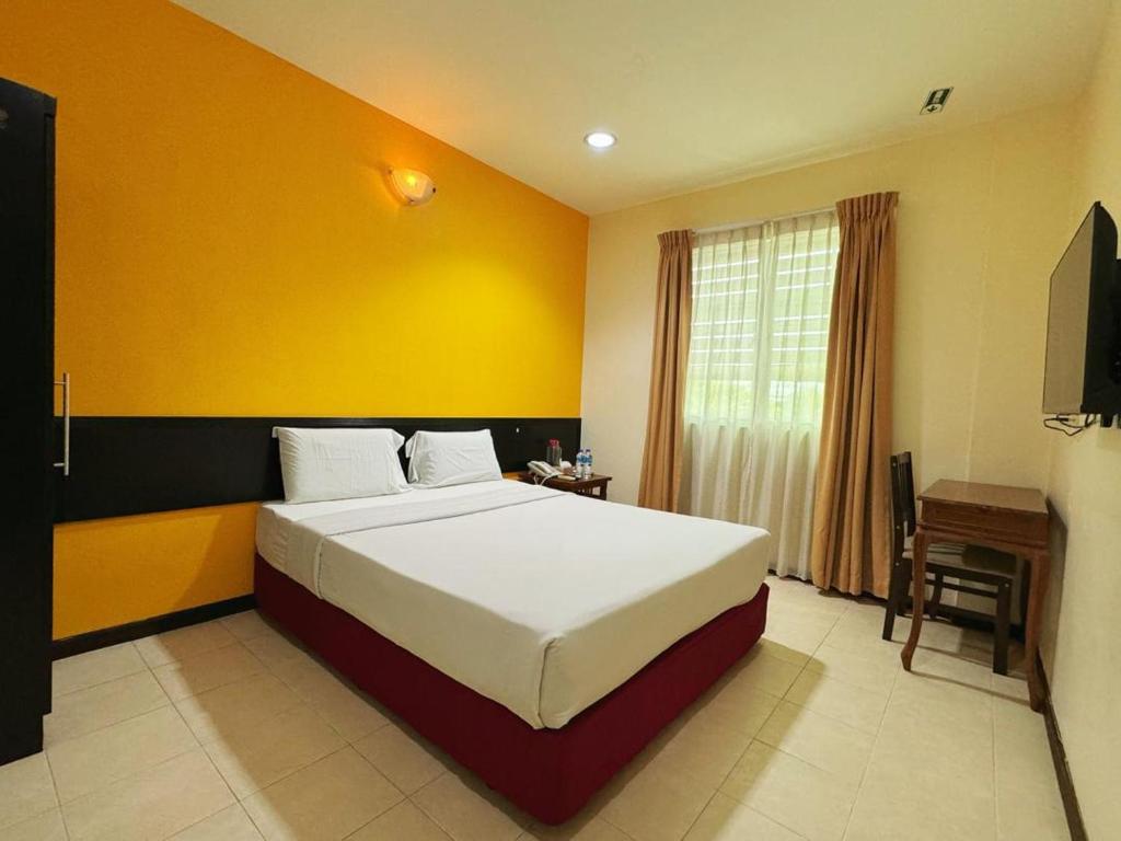 马西GRAND FAR EAST HOTEL SDN BHD的一间卧室设有一张床和黄色的墙壁