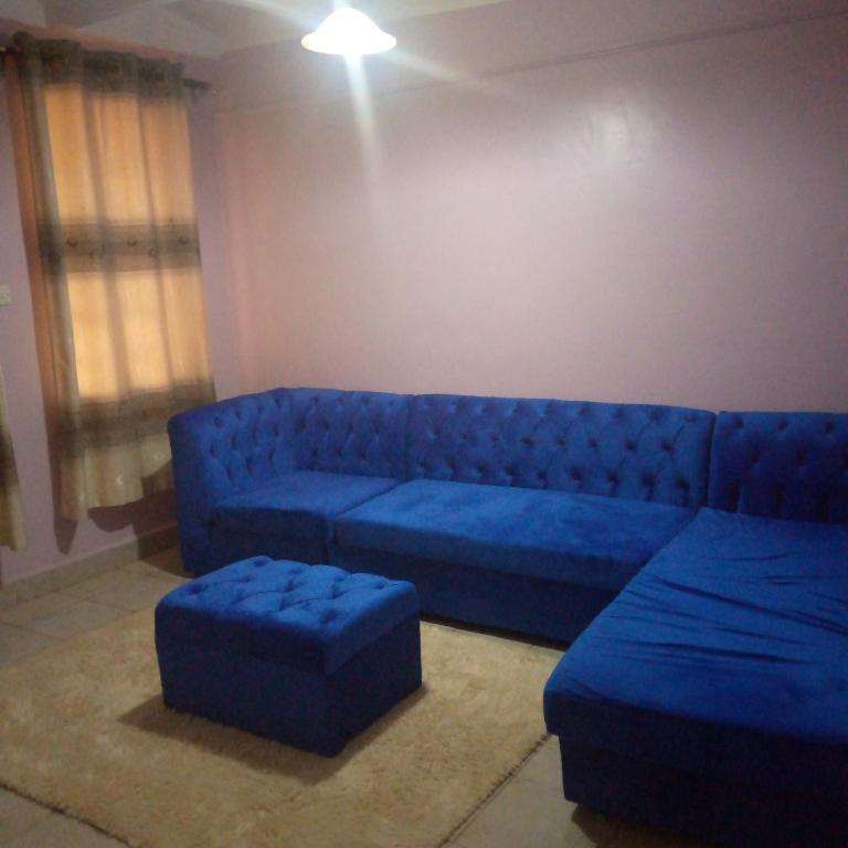 ThikaVerona Apartments的客厅里一张蓝色的沙发和搁脚凳