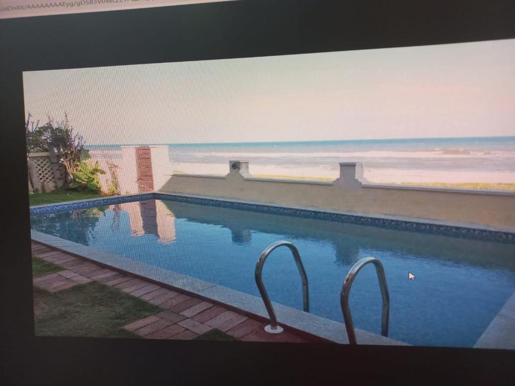 钦奈Happy Beach House的电视屏幕显示一个享有海滩景色的游泳池