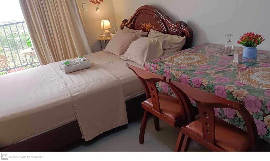 Lapu Lapu CityAdam&Eva Condo Staycation的一间卧室配有一张床和一张桌子及椅子