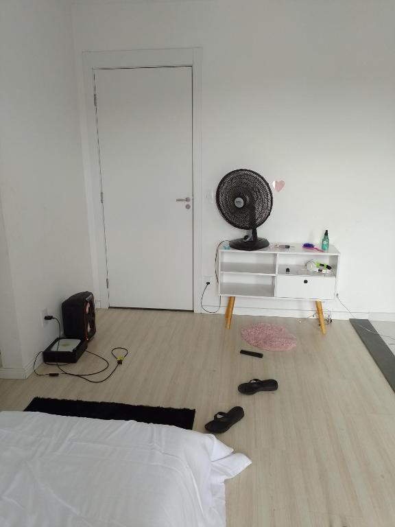 里约热内卢Aconchego Hostel的一间卧室配有一张床和一张带风扇的桌子。