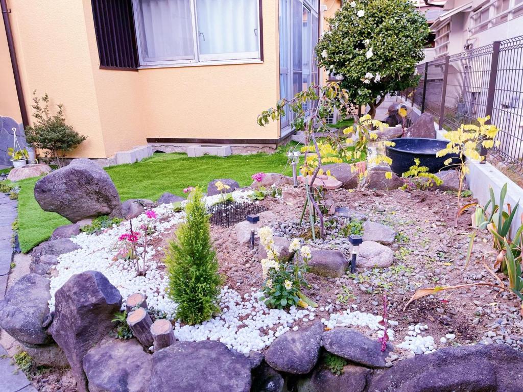 丰中Otami Stay的一座花园,在房子前面有岩石和植物
