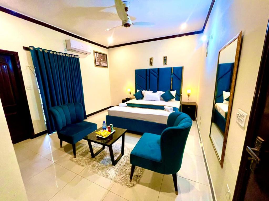 拉合尔Go Guest House Lahore的一间卧室配有一张床、两把椅子和一张桌子