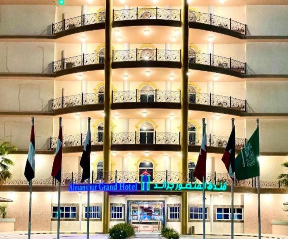 哈费尔巴廷Al Mansour Grand Hotel的前面有旗帜的大建筑