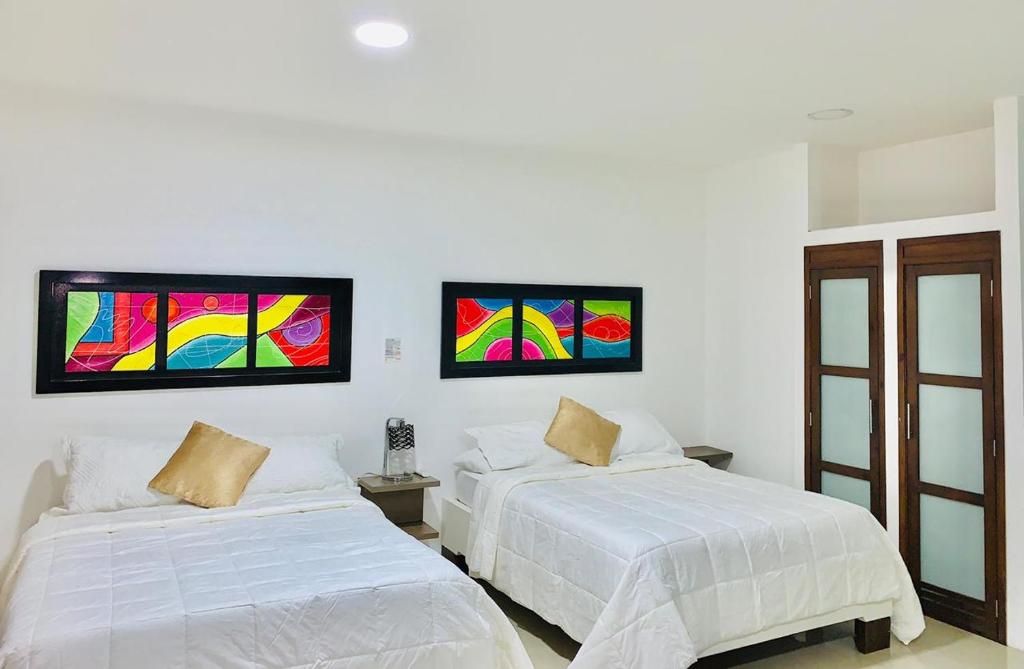 圣安德烈斯Apartahotel Bahia Tropical II的一间卧室设有两张床,墙上挂有绘画作品