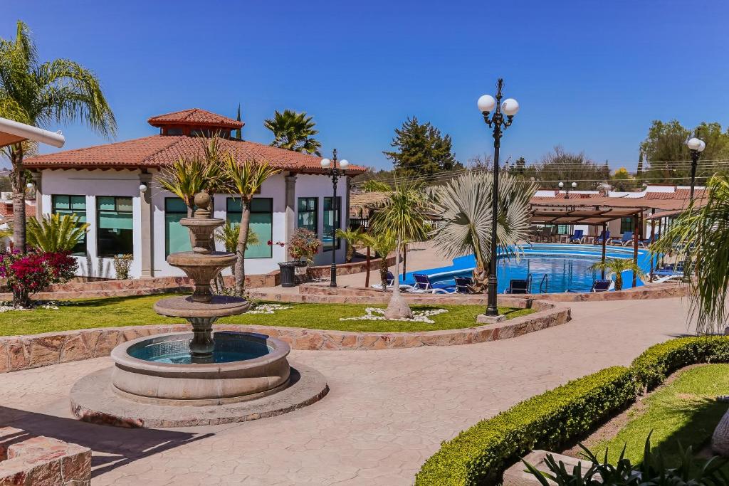特基斯基亚潘圣何塞雷亚尔酒店的喷泉位于带游泳池的度假村前