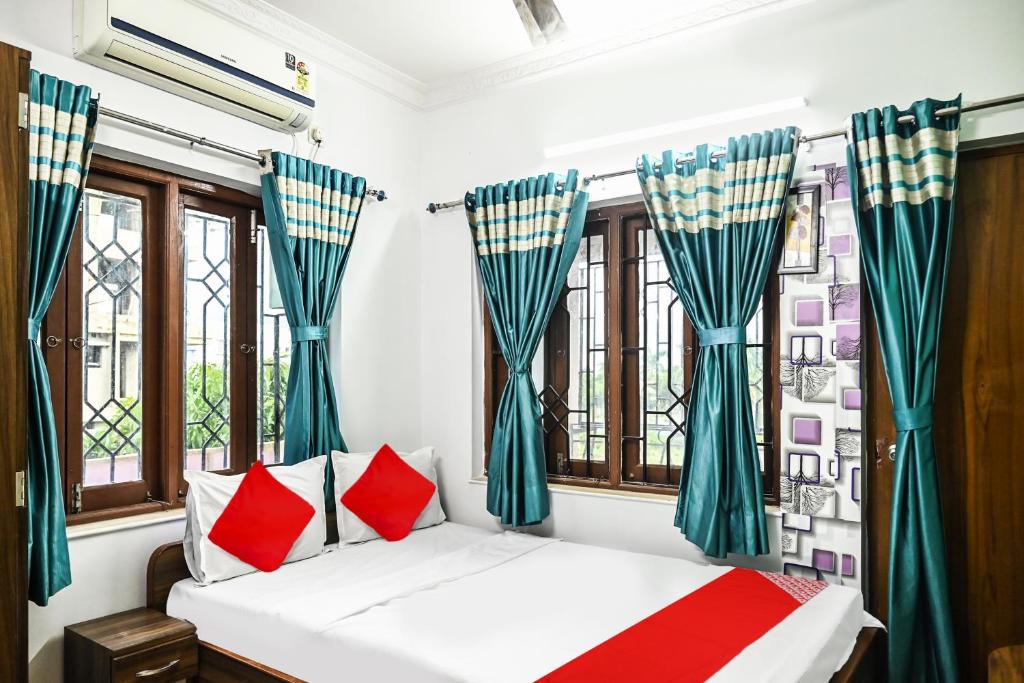 加尔各答OYO Flagship Shraddha Residency 2的一间卧室配有红色和蓝色窗帘的床