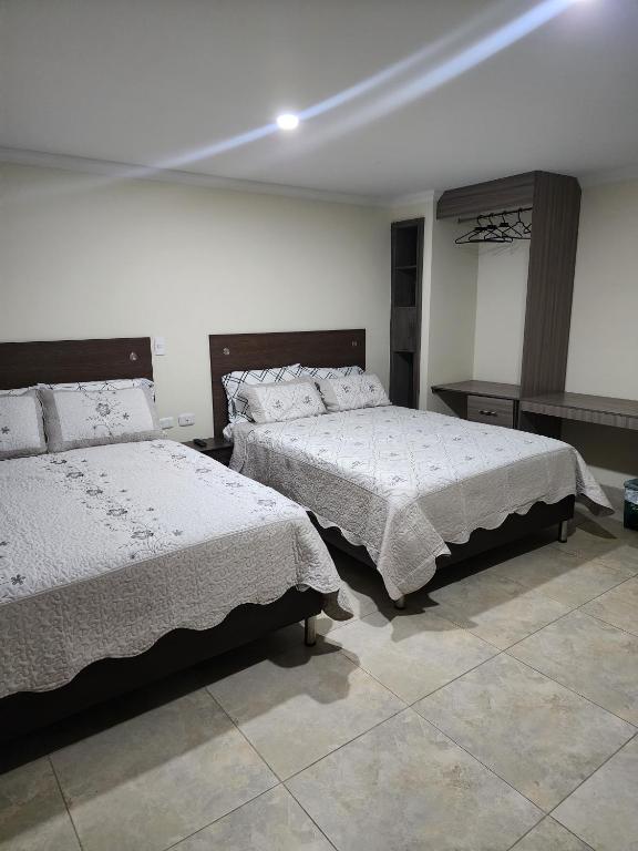 波哥大HOTEL CASA MARED Corferias-Embajada Americana的一间卧室配有两张带白色棉被的床