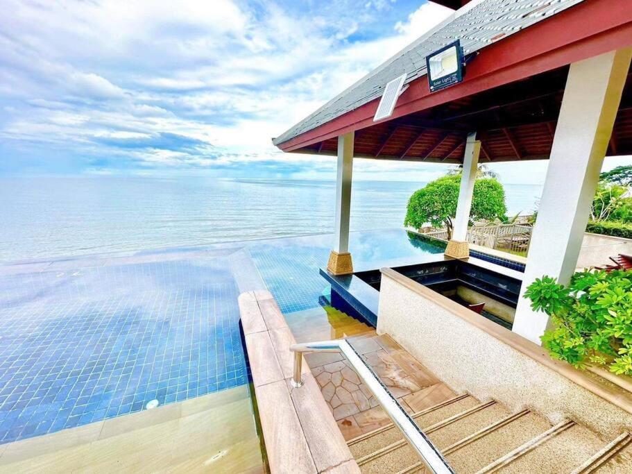 华欣Happy Life Seaview @PalmPavillion的水边的房屋,设有游泳池