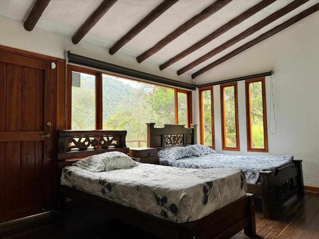 El SalitreTermales azules La Calera的配有窗户的客房内的两张床