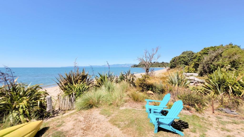 Parapara Parapara's Seaview Retreat的海滩上靠近水面的蓝色椅子