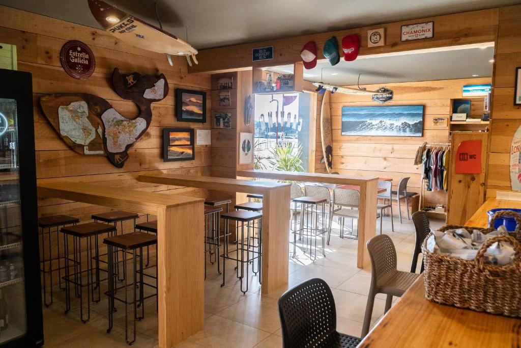 San Esteban de PraviaCarving Surf Hostel的餐厅内的酒吧,设有木墙和酒吧凳子