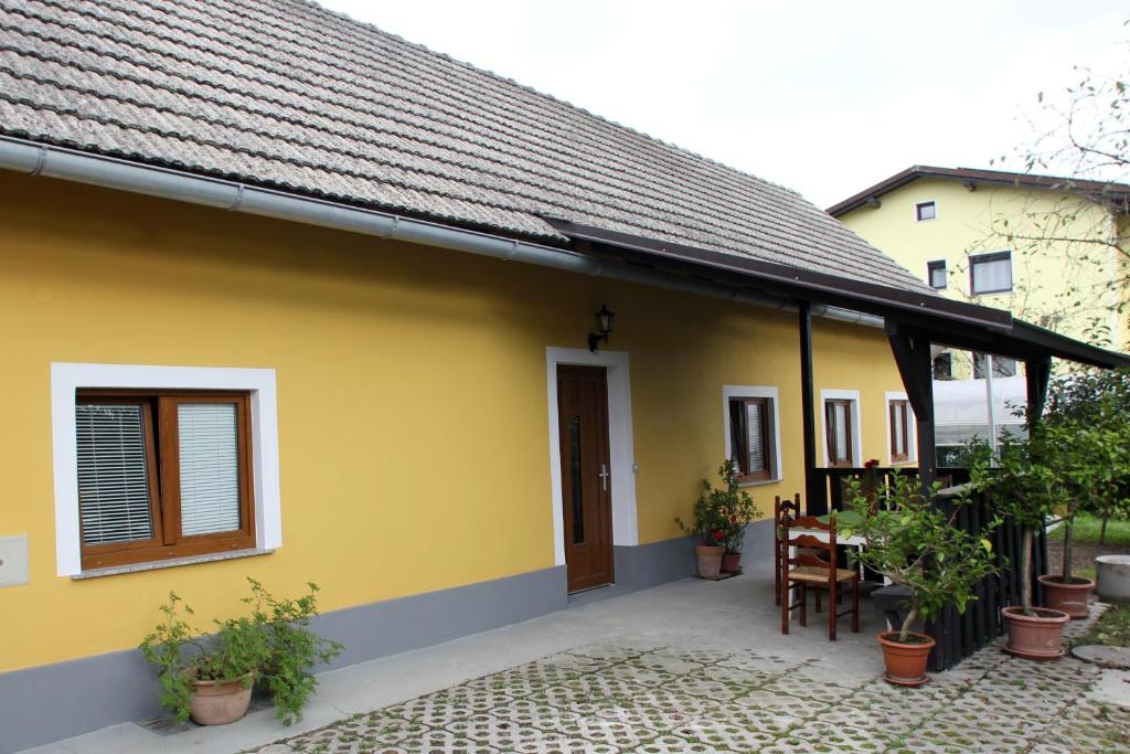 多姆扎莱Kmečka hiša Rodica的黄色的房子,设有门廊,配有桌子和椅子