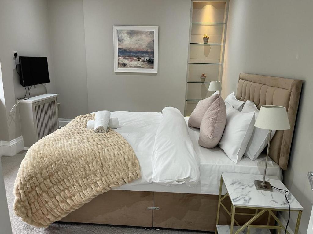 伦敦Central Park Aparthotel的一间卧室配有带白色床单和枕头的床。