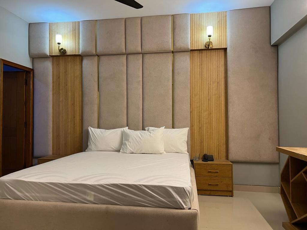 卡拉奇Marigold Accommodations的一间卧室配有带白色床单和枕头的床。