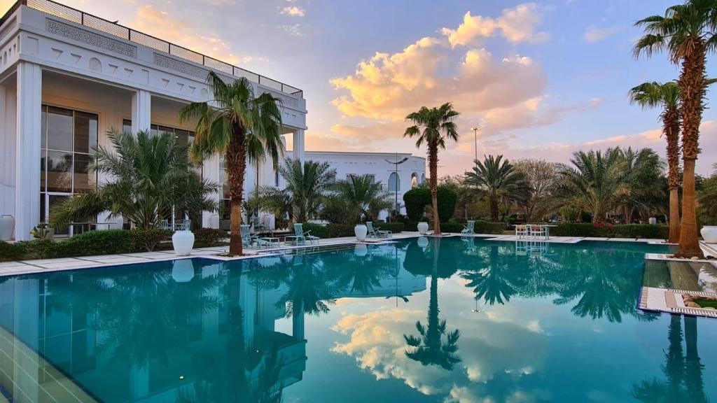 Al ‘UyūnBeit Al-Madina的一座楼前种有棕榈树的游泳池