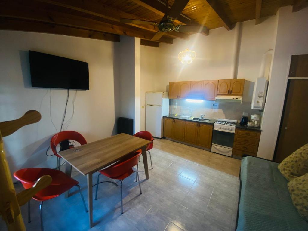 内乌肯Cerquita de Shopping: depto amoblado urbano的厨房配有木桌和红色椅子