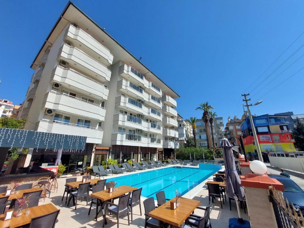 阿拉尼亚蓝色天堂公寓式酒店的一座带桌椅的游泳池位于酒店大楼旁