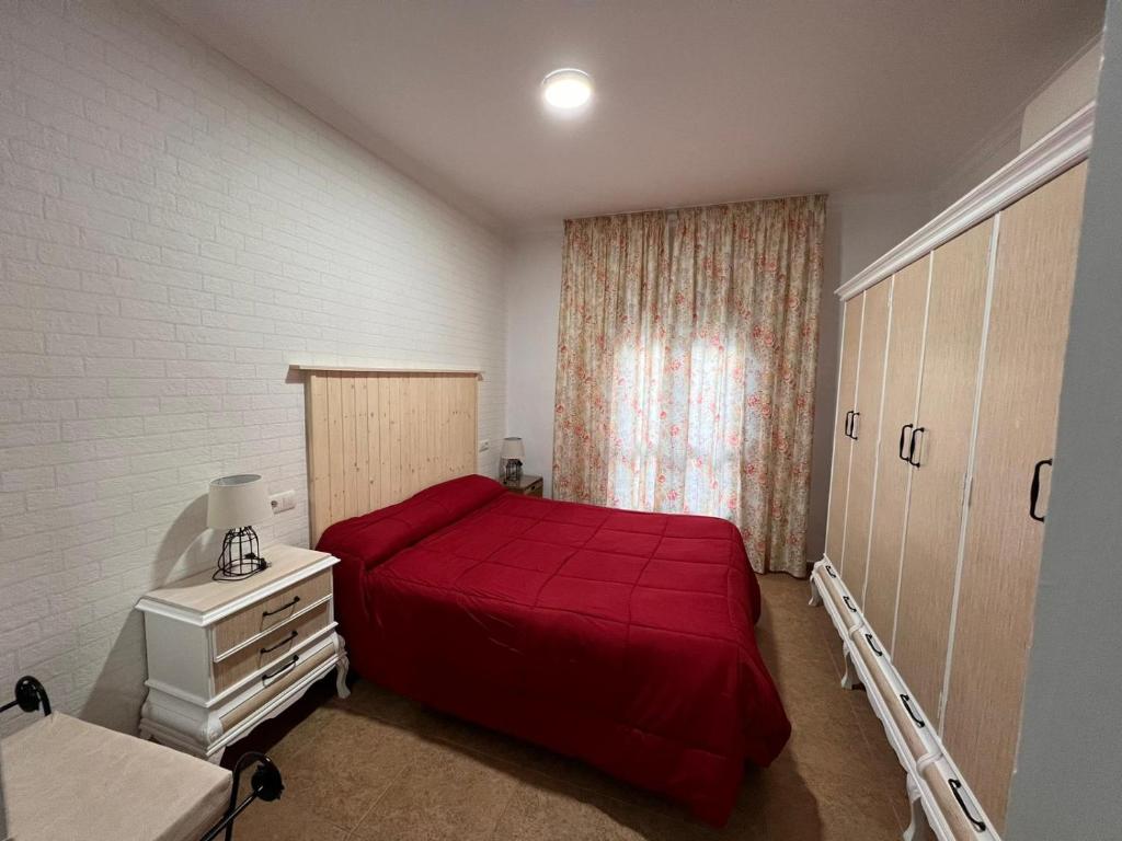 阿达莱斯Apartamentos Virgen de Villaverde的一间卧室设有红色的床和窗户。