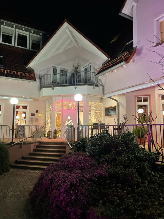 莱因斯韦勒山庄酒店及餐厅的白色的房子,有楼梯和紫色的鲜花