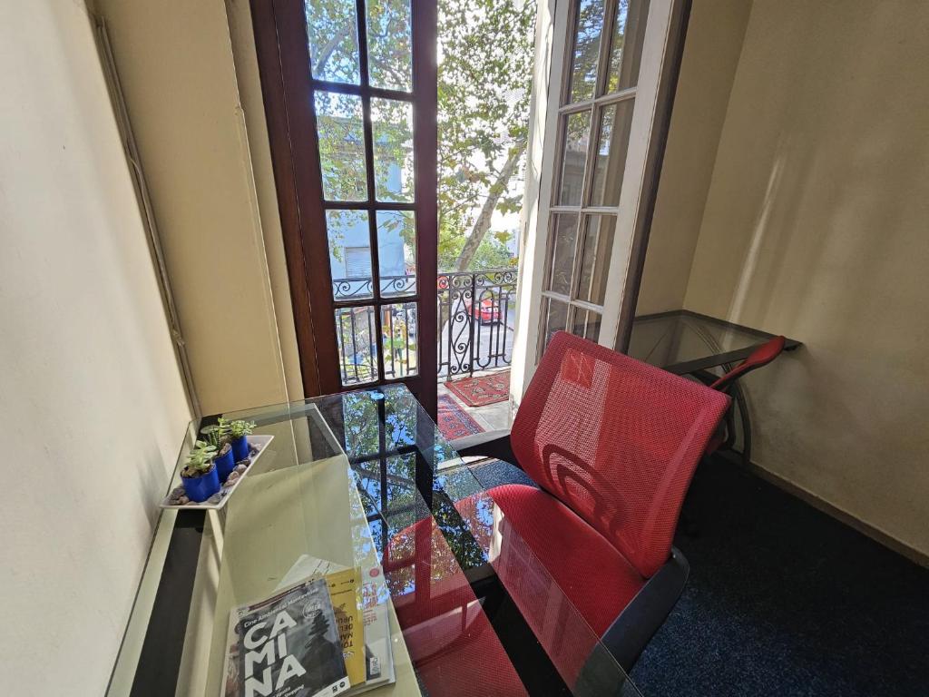 蒙得维的亚Montevideo Hostel的一间设有玻璃桌和红色椅子的房间