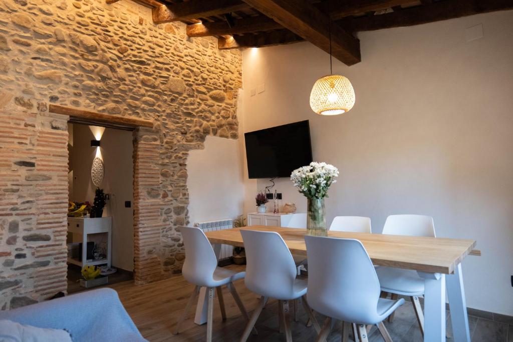 维克Niu de Queralt的一间带木桌和白色椅子的用餐室