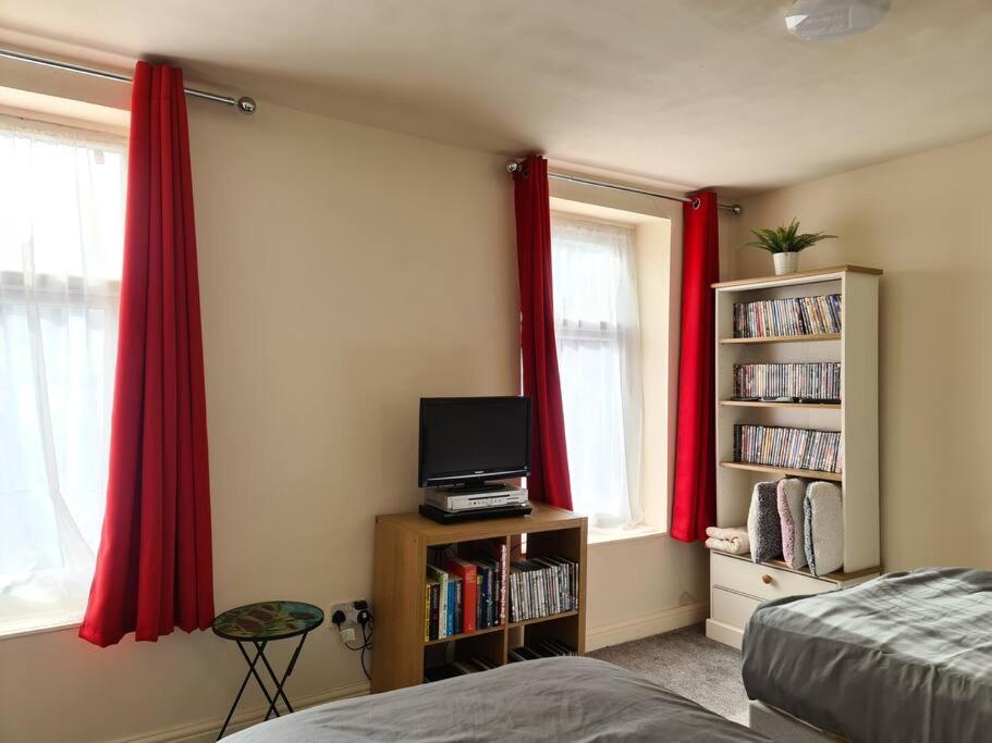 阿什顿下安林恩Ideal Apartment close to the Hustle and Bustle的一间带红色窗帘、一张床和电视的卧室