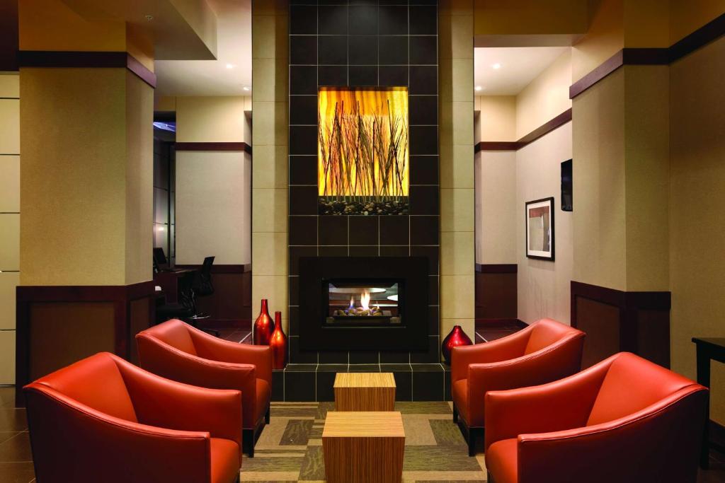 德梅因梅因市中心凯悦嘉轩酒店的一间设有红色椅子和壁炉的等候室