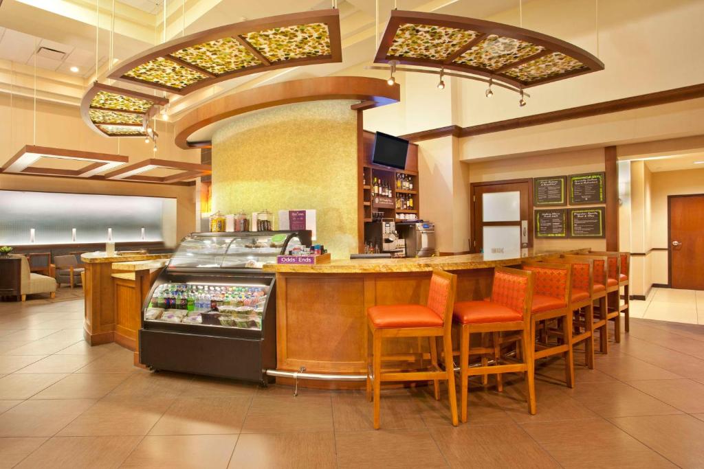 奥兰多奥兰多机场广场凯悦酒店的餐厅设有酒吧,配有橙色椅子和柜台