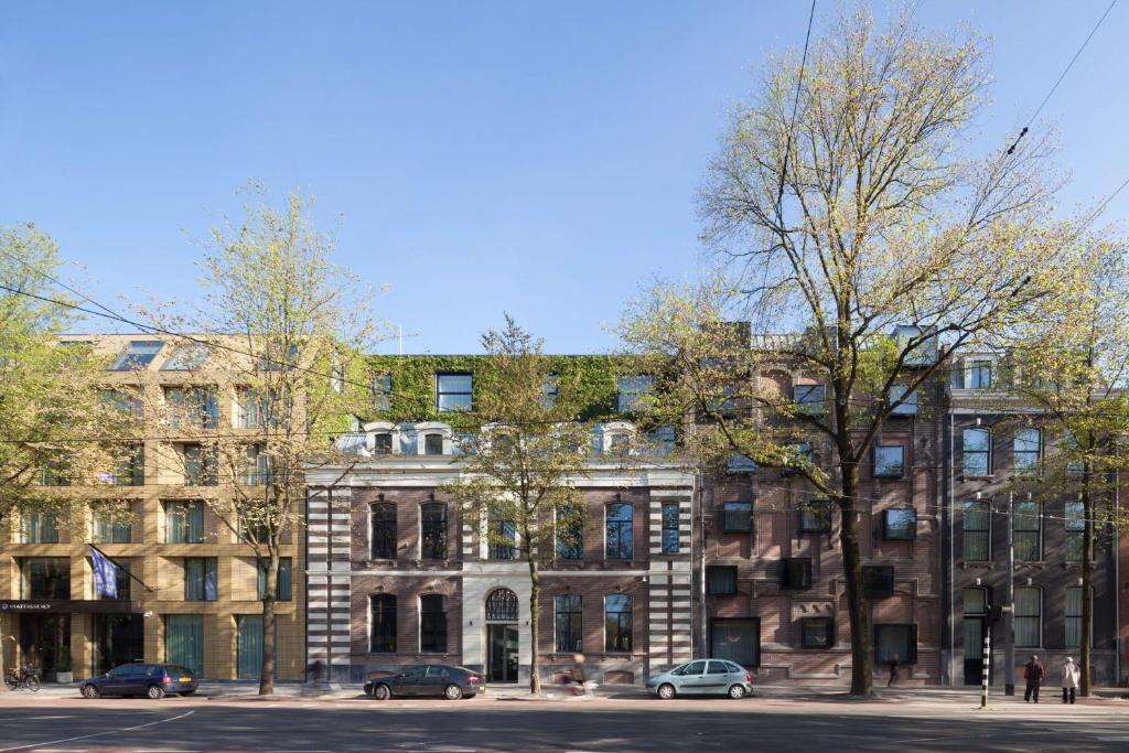阿姆斯特丹阿姆斯特丹凯悦酒店的一座大型砖砌建筑,前面有汽车停放