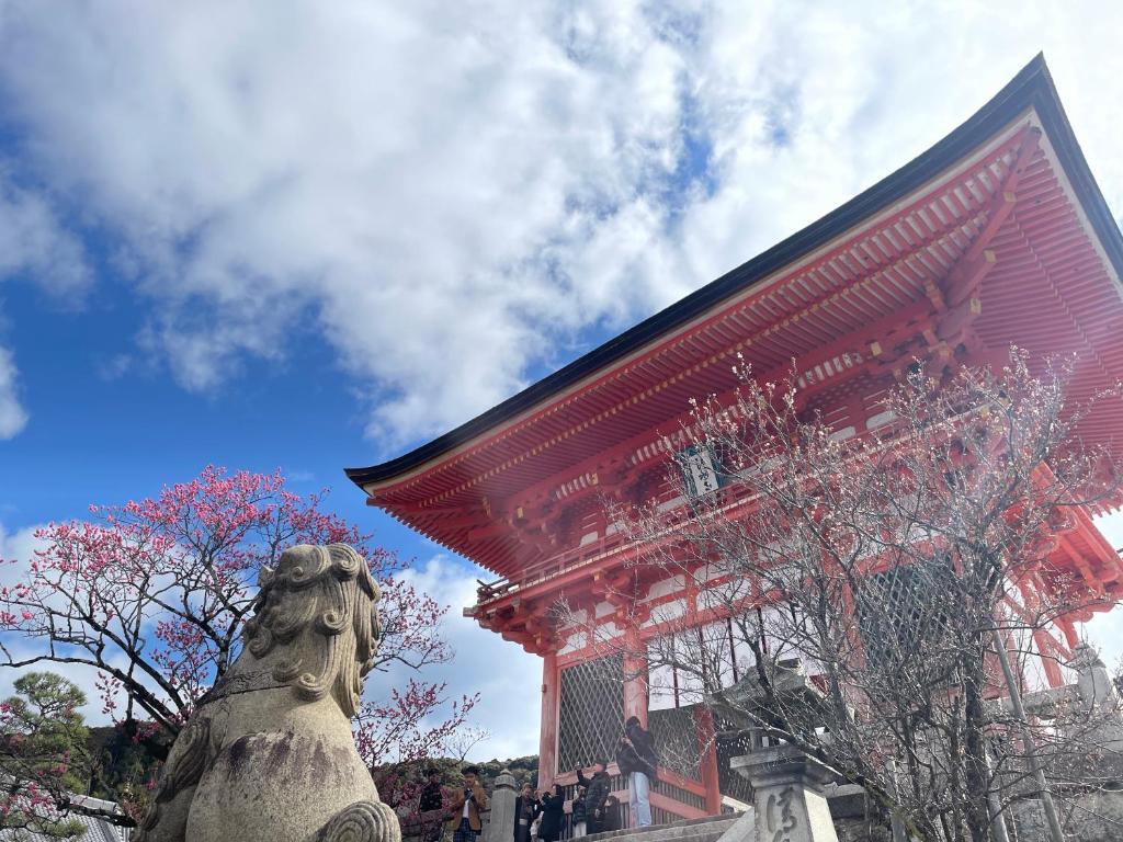 京都HOTEL AMANEK Kyoto Kawaramachi Gojo的一座红色的建筑,前面有雕像