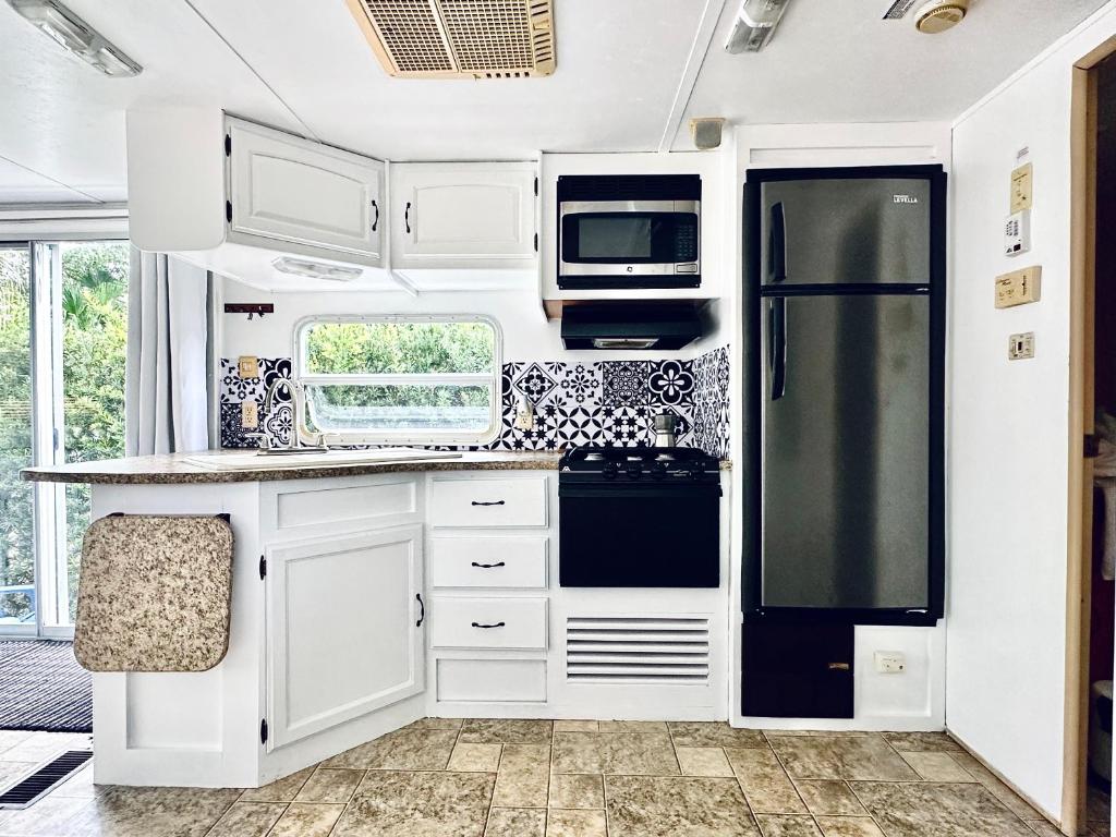 迈阿密Descanso, tranquilidad y desconexión a un paso de todo.的厨房配有白色橱柜和黑色冰箱。