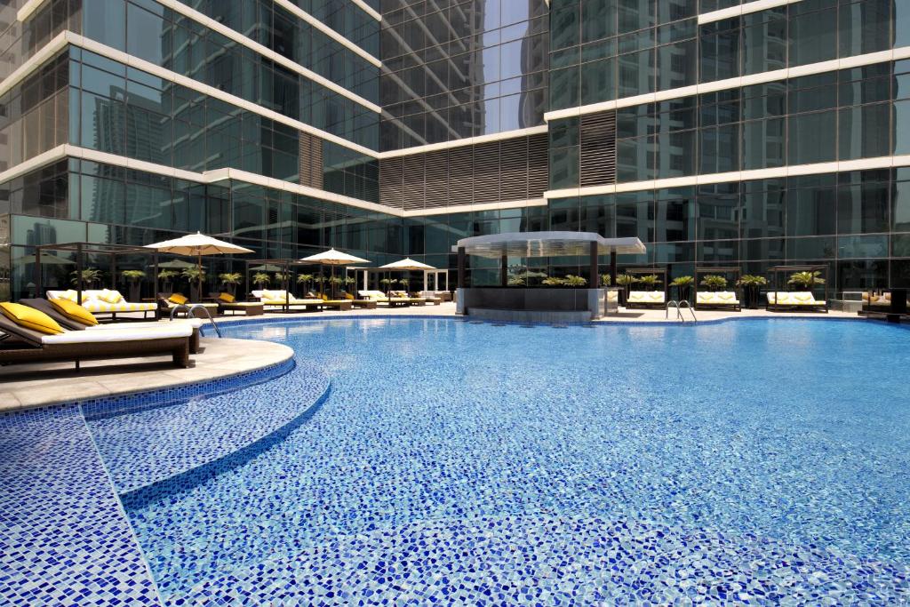 迪拜迪拜皇冠酒店的一座带椅子的大型游泳池和一座建筑