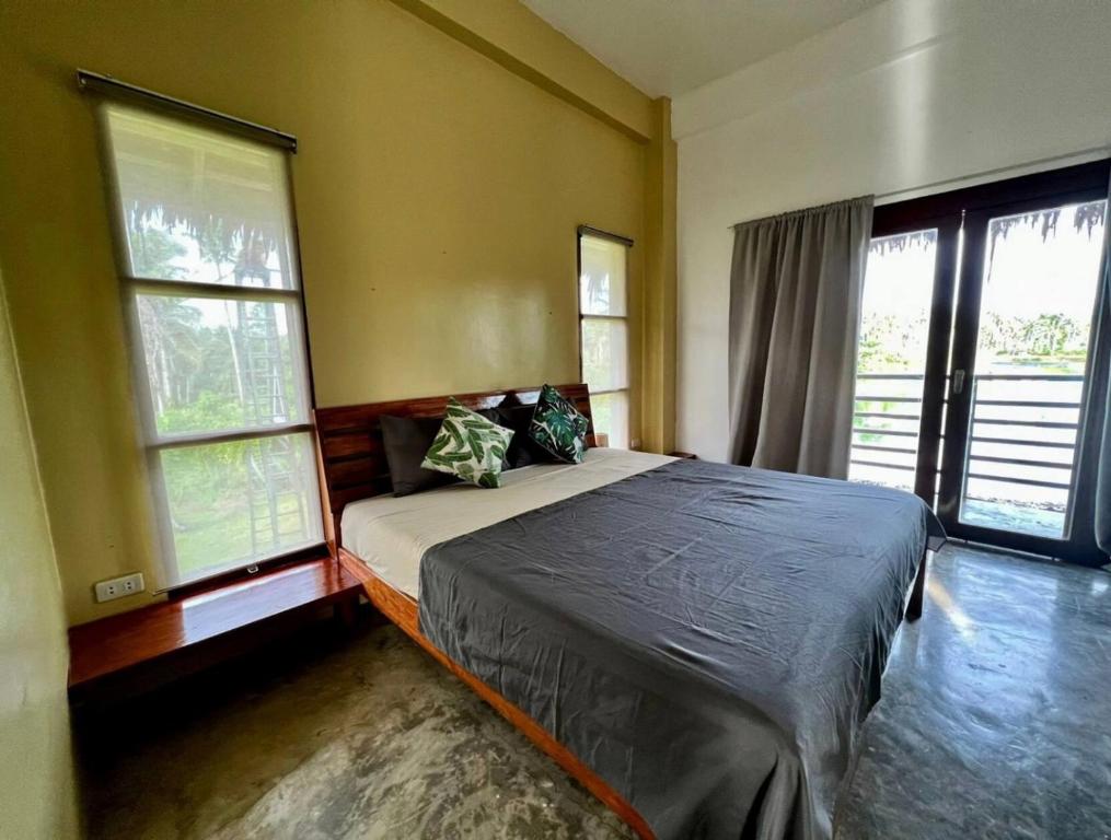 卢纳将军城Siargao Wakepark的一间卧室设有一张床和两个窗户。
