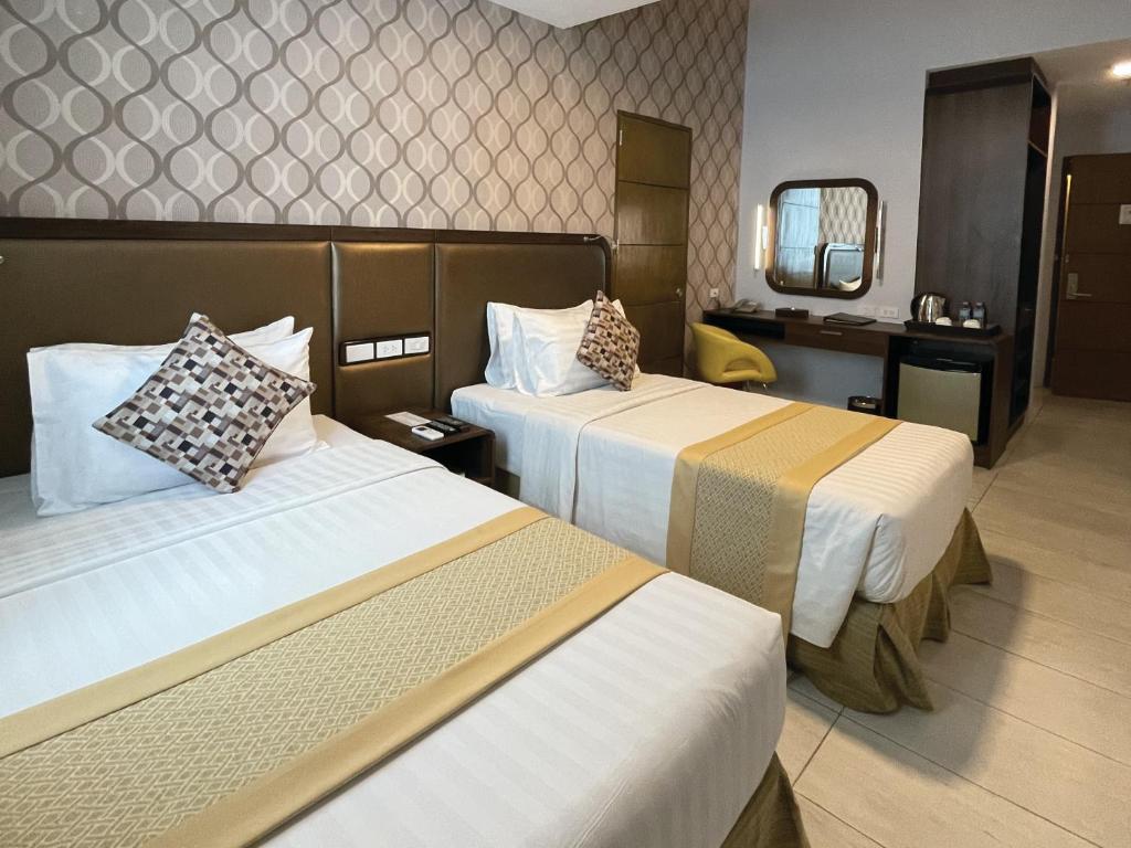 宿务One Central Hotel & Suites的酒店客房,设有两张床和镜子