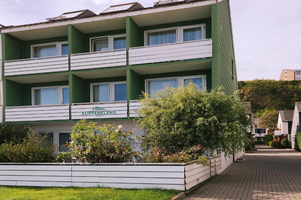 黑尔戈兰岛Hotel Klippenklang的一座绿色的白色建筑,前面有灌木丛