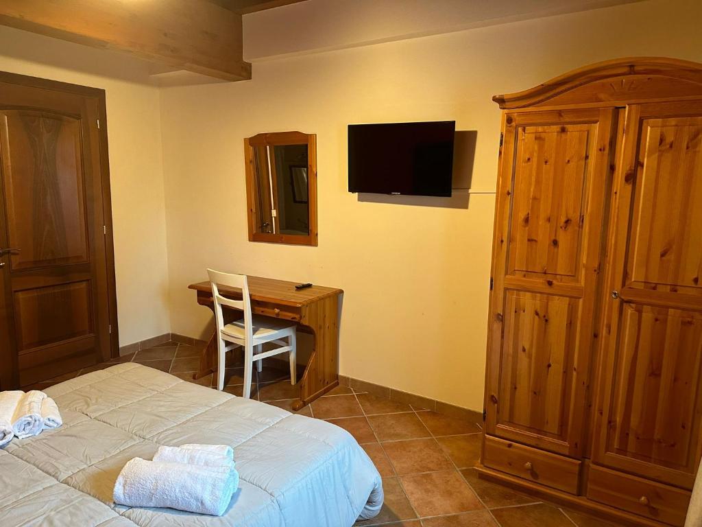 PolazzoLa corte dell'ulivo的一间卧室配有一张床和一张书桌及电视