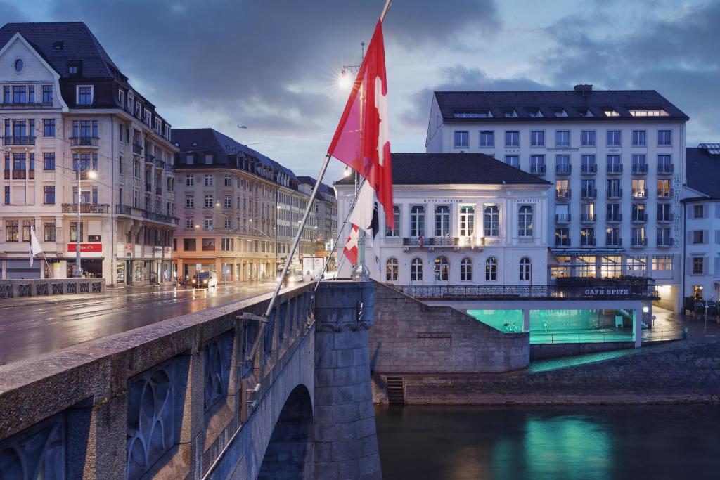 巴塞尔Merian Basel - Self Check-in的河上两面有旗帜的桥梁
