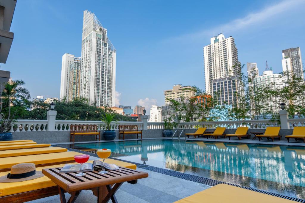 曼谷曼谷素坤逸大道酒店的一座带桌椅的游泳池以及大楼