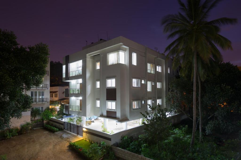 班加罗尔Sanctum Suites BEL Road Bangalore的一座白色的大建筑,晚上有棕榈树