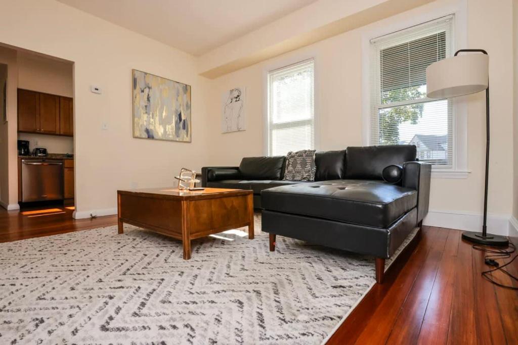 马尔登Stylish Apartment in Malden 20 Min from Boston #2的客厅配有黑色真皮沙发和咖啡桌