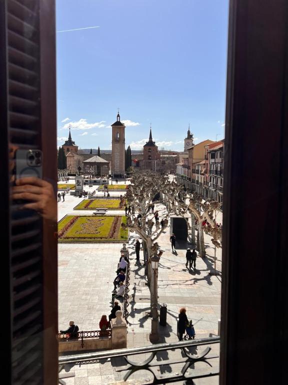 阿尔卡拉德荷那利斯Sueña en la Plaza Cervantes的把城市的照片从窗口拍下来的人