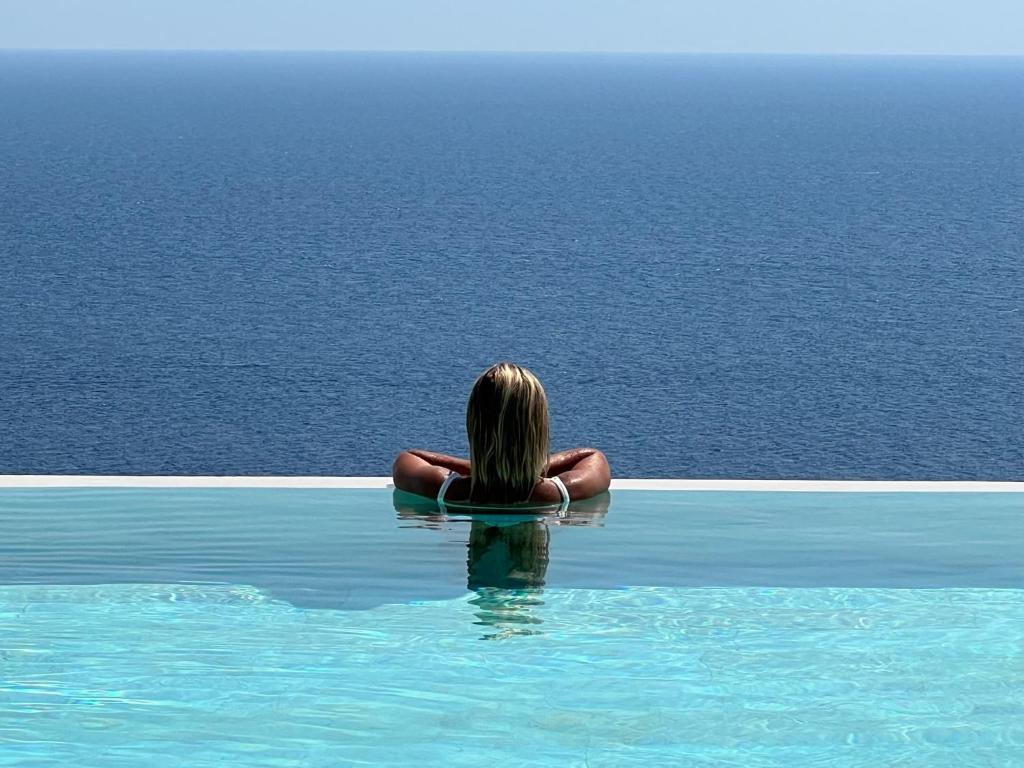 圣凯撒利亚温泉Le Capase Resort Salento的坐在游泳池里看着大海的女人