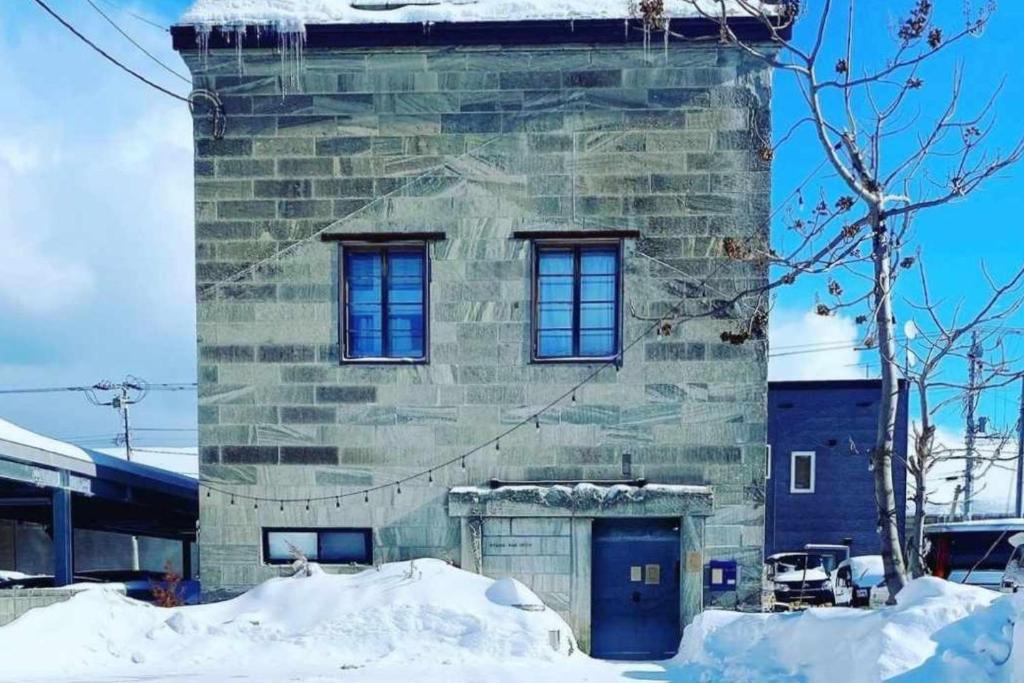小樽石と鉄-House of STONE and IRON的一座石头建筑,设有两扇窗户和一扇蓝色的门