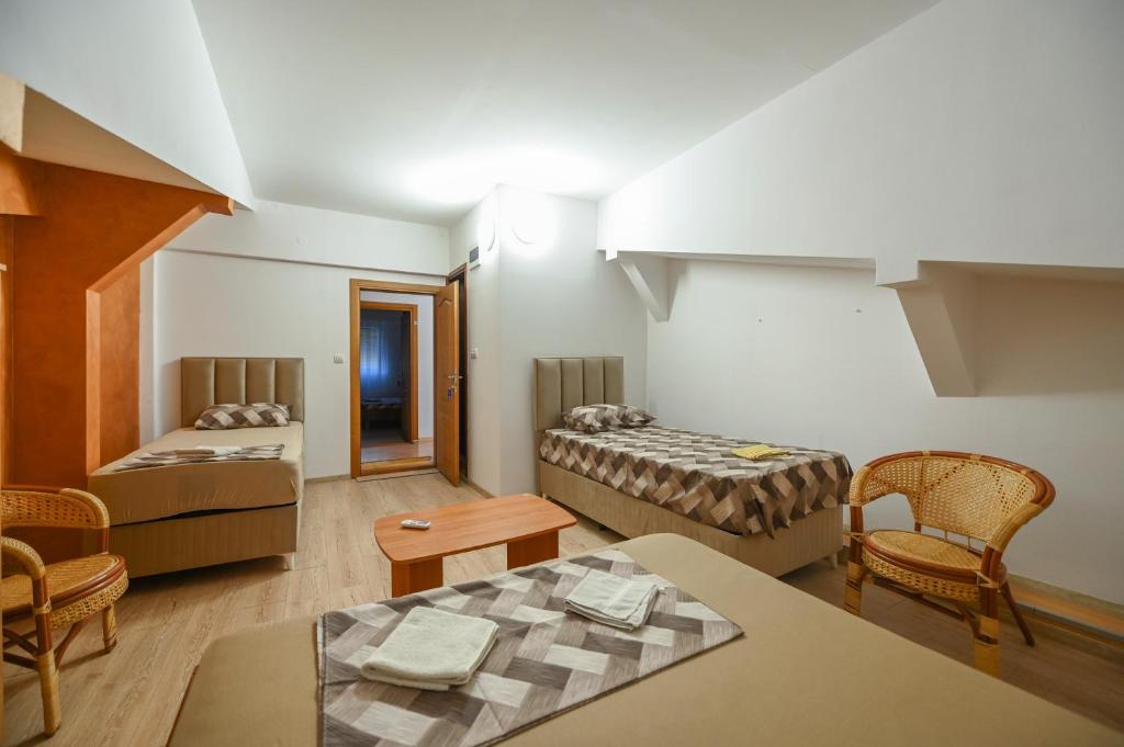 波德戈里察伊兹沃尔旅馆的一间设有两张床和一张桌子及椅子的房间