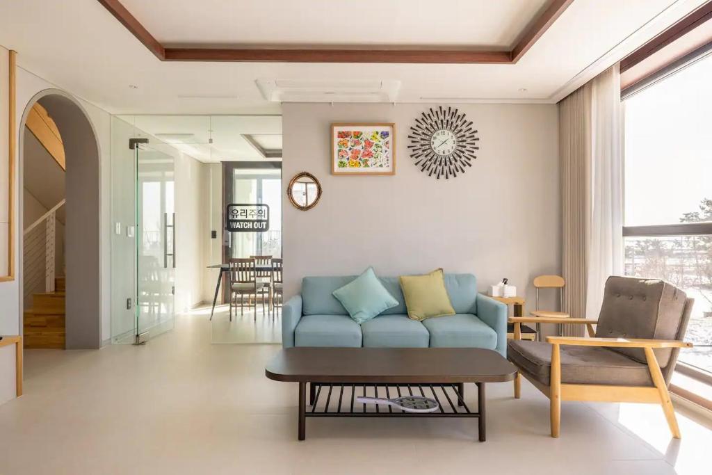 仁川市Miracle Suite house 201 pool villa的客厅配有蓝色的沙发和桌子