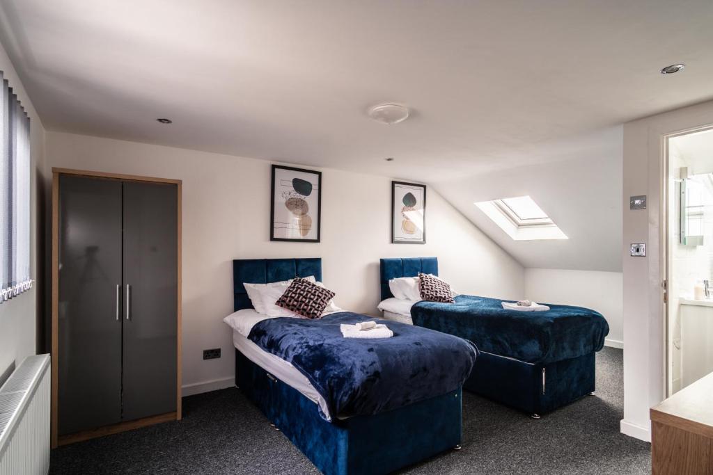 曼彻斯特Refined Comforts for Two Room 5的一间卧室配有两张床和两只蓝色的矮脚凳