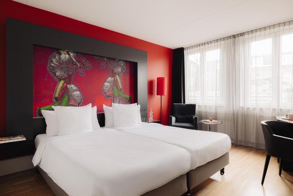 马斯特里赫特马斯特里赫特设计酒店的一间卧室设有一张大床和红色的墙壁