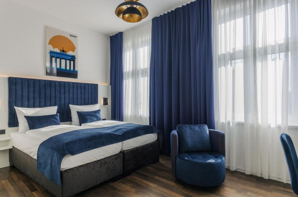 柏林Homaris East Side Hotel - Mobile Key Access的一间卧室配有蓝色窗帘、一张床和椅子