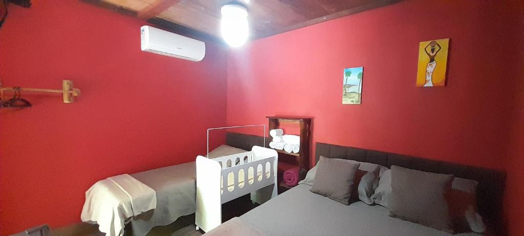 库穆鲁沙蒂巴Chalés Guigó-Cumuruxatiba的红色卧室配有床和镜子